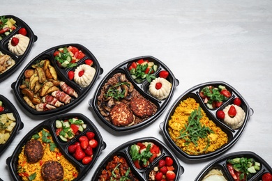 Lunchboxes with different meals on white table, flat lay. Healthy food delivery