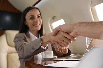 Colleagues shaking hands in airplane during flight
