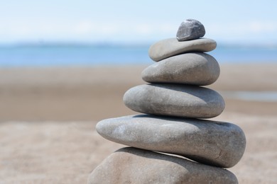 Stack of stones on beautiful sandy beach near sea, closeup. Space for text