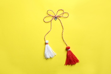 Photo of Traditional martisor on yellow background, top view. Beginning of spring celebration