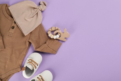 Flat lay composition with baby clothes and accessories on violet background, space for text
