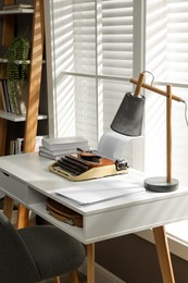 Comfortable writer's workplace interior with typewriter on desk in front of window