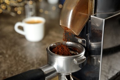 Photo of Pouring ground coffee from grinding machine into portafilter, closeup