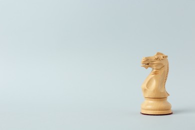 Wooden knight on light background, space for text. Chess piece