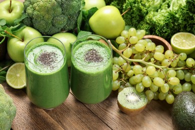 Glasses of fresh green smoothie and ingredients on wooden table