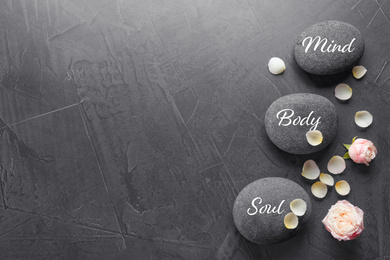 Stones with words MIND, BODY, SOUL on grey background, top view with space for text. Zen lifestyle
