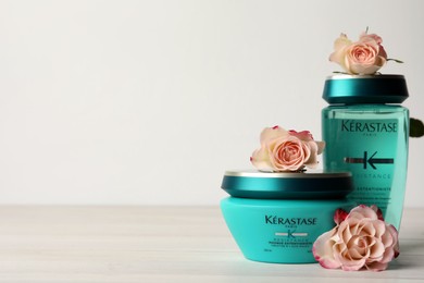 MYKOLAIV, UKRAINE - SEPTEMBER 07, 2021: Kerastase hair care cosmetic products and beautiful flowers on white wooden table. Space for text