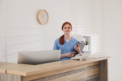 Receptionist with document cases at countertop in hospital