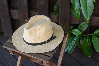 Stylish hat on wooden stool near fence. Beach accessory