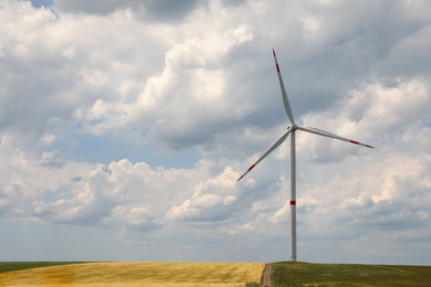 Modern wind turbine in field on cloudy day. Alternative energy source