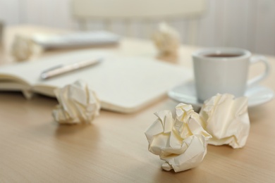 Sheets of crumpled paper and cup on wooden table, space for text