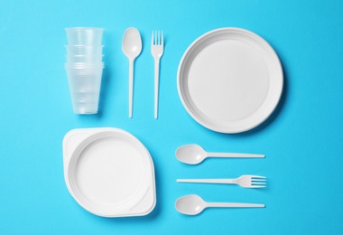 Flat lay composition with disposable tableware on light blue background