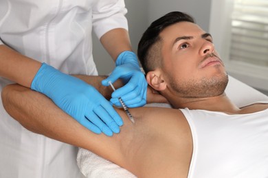 Cosmetologist injecting man's armpit in clinic. Treatment of hyperhidrosis
