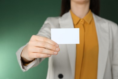 Photo of Woman holding white business card on green background, closeup