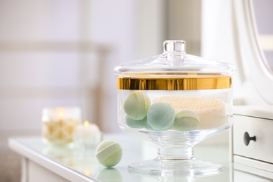 Jar with bath bombs and bath sponge on dressing table indoors