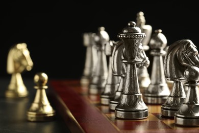 Chessboard with game pieces on black background, closeup
