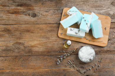 Flat lay composition with natural handmade soap and ingredients on wooden table, space for text
