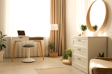 Stylish room interior with chest of drawers and round mirror