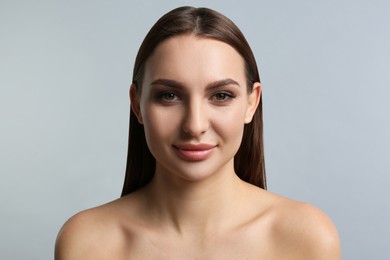 Portrait of beautiful young woman with plump lips on light grey background
