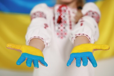 Little girl with painted hands near Ukrainian flag, closeup. Love Ukraine concept