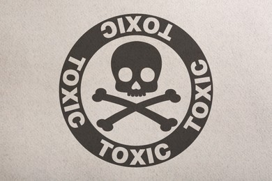Hazard warning sign (skull-and-crossbones symbol and word TOXIC) on paper, top view
