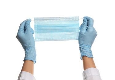 Doctor in latex gloves holding disposable face mask on white background, closeup. Protective measures during coronavirus quarantine