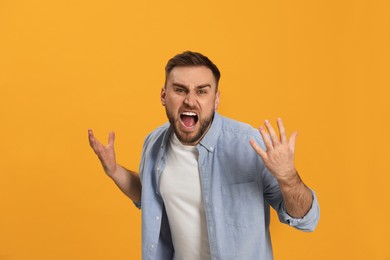 Photo of Angry young man on yellow background. Hate concept