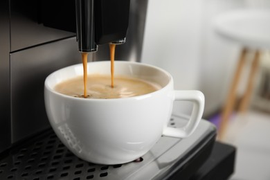Espresso machine pouring coffee into cup against blurred background, closeup