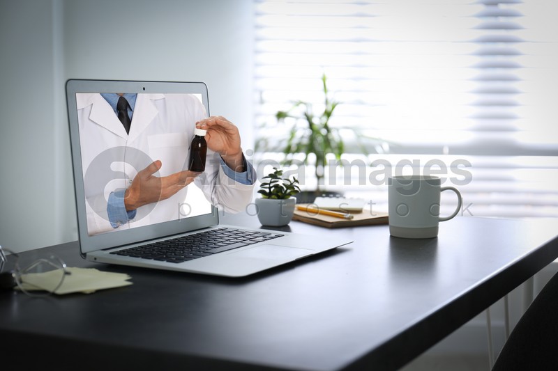 Image of Ordering medications online. Pharmacist giving pills from laptop screen
