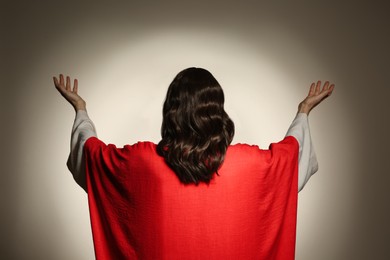 Jesus Christ with outstretched arms on beige background, back view