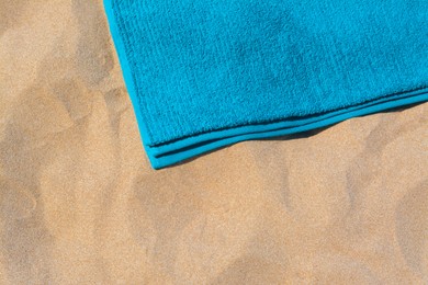 Photo of Soft blue beach towel on sand, above view. Space for text