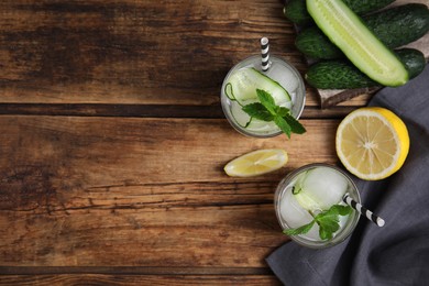 Photo of Tasty fresh cucumber water and ingredients on wooden table, flat lay. Space for text