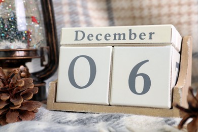 Saint Nicholas Day. Block calendar with date December 06 and festive decor on plaid, closeup