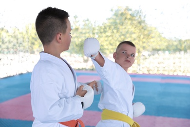 Photo of OCHAKIV, UKRAINE - JULY 09, 2020: Children in kimono practicing karate in pavilion. Summer camp "Sportium"