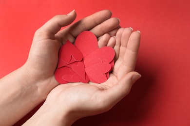 Woman holding paper hearts on red background, closeup. Happy Valentine's Day