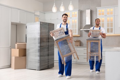 Photo of Male movers carrying chairs in new house