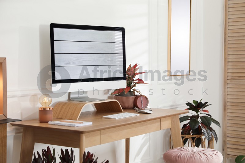 Photo of Comfortable workplace with modern computer and beautiful plants in room. Interior design