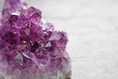Photo of Beautiful purple amethyst gemstone on grey table, closeup view. Space for text