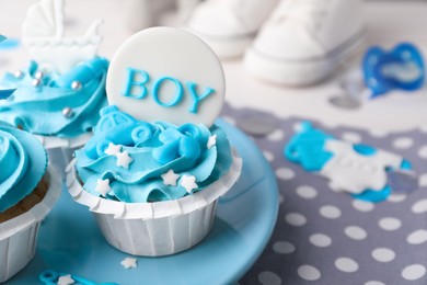 Delicious cupcakes with light blue cream and toppers for baby shower on table, closeup