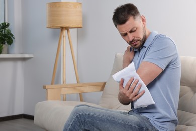 Man using heating pad at home, space for text