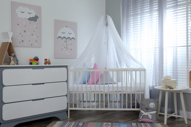 Baby room interior with cute posters, chest of drawers and comfortable crib
