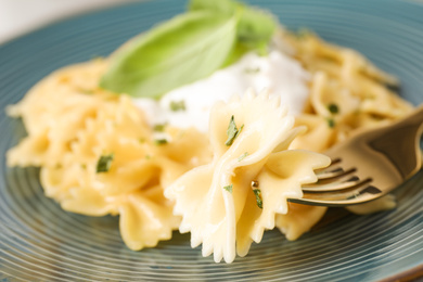 Tasty farfalle pasta with herbs on fork, closeup
