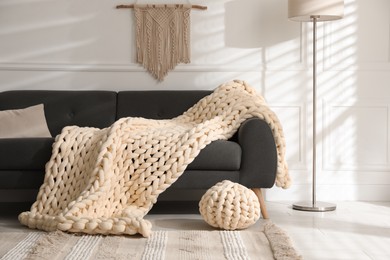 Soft chunky knit blanket on sofa in living room. Interior design