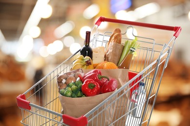 Shopping cart with different groceries in supermarket