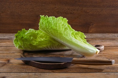 Halves of fresh ripe Chinese cabbage and knife on wooden table