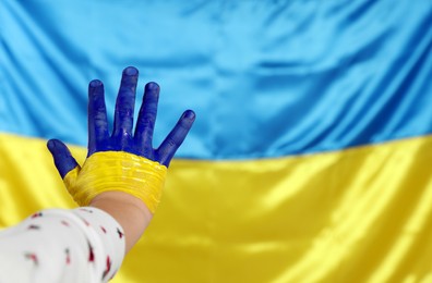 Photo of Little girl with paint on hand near Ukrainian flag, closeup. Space for text