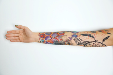 Woman with colorful tattoos on arm against white background, closeup