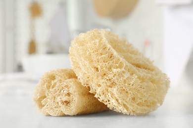 Natural loofah sponges on table in bathroom, closeup