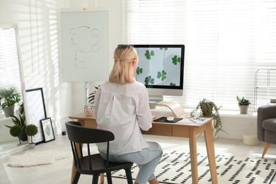 Photo of Woman working at table in light room, back view. Home office