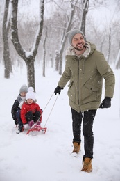 Photo of Father sledding his children outside on winter day. Christmas vacation
